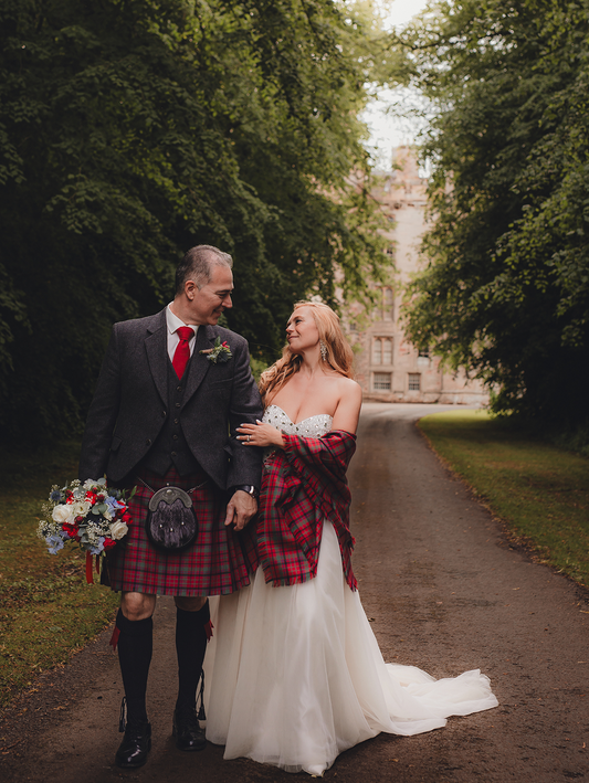 A bride and groom pose for a photo outside a castle